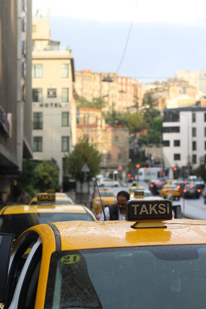 why-choose-us Yellow taxis line a bustling street in a vibrant city after rain.