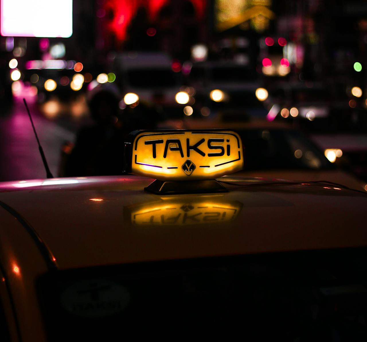 gallery-1 Nighttime scene in Istanbul featuring an illuminated taxi sign against a backdrop of city lights.